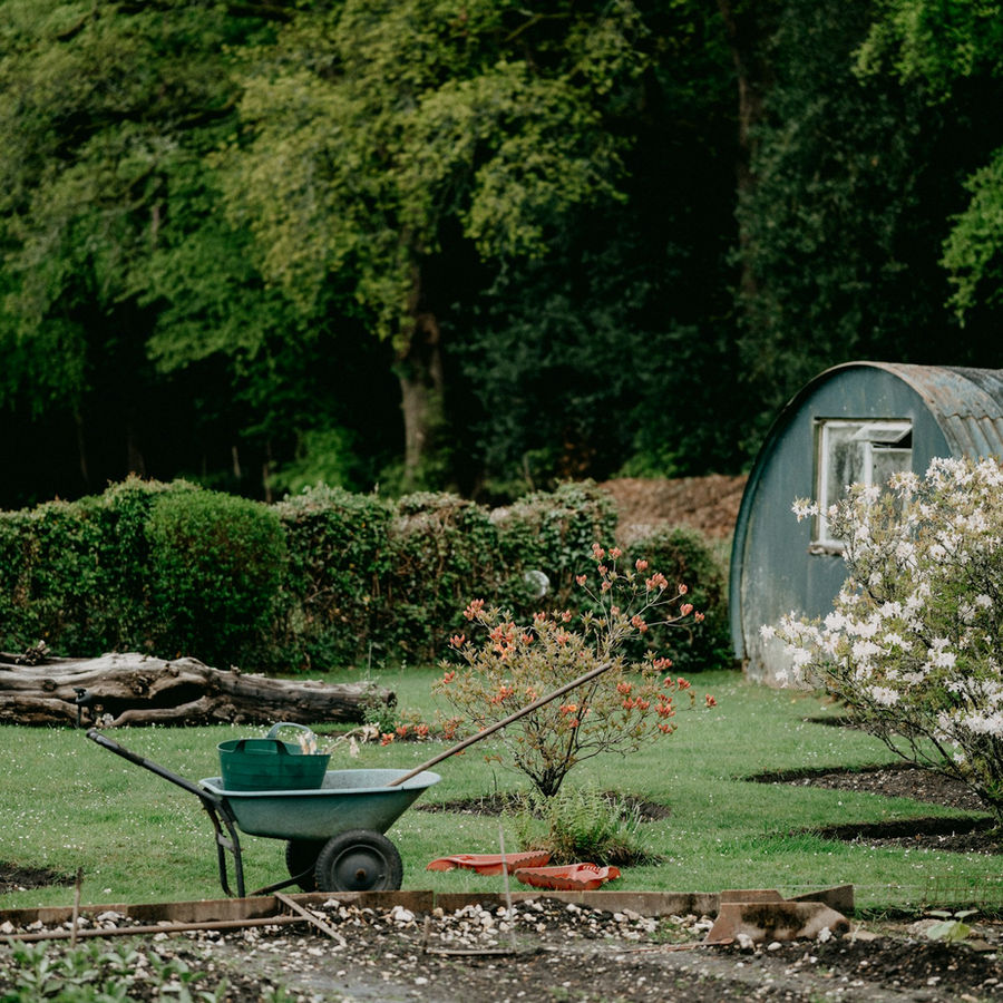 Gepflegter Garten mit Schubkarre und Gartenhaus